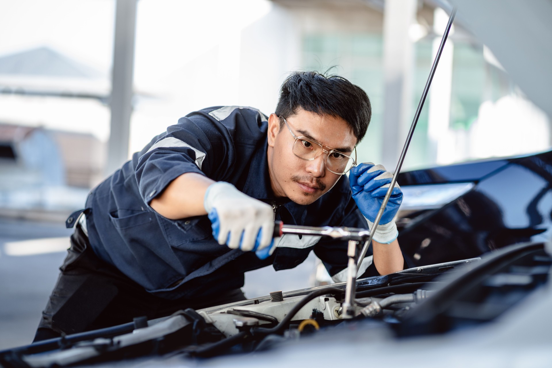 Auto mechanic repairman using a socket wrench working engine repair in the garage, changing spare parts, checking the mileage of the car, maintaining service automobile car