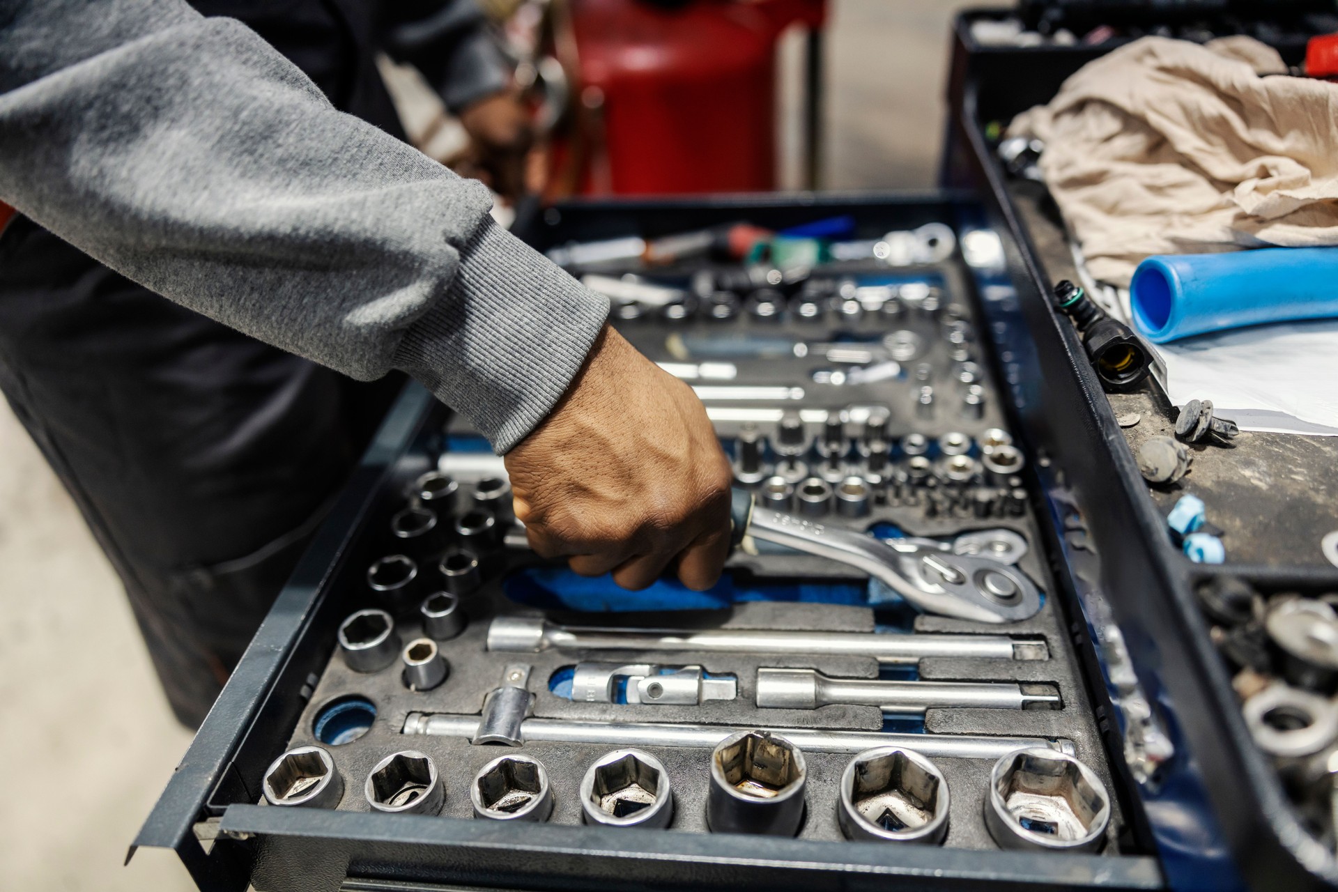 Close up of multicultural mechanic's hand taking wrench from toolbox at auto mechanic workshop.